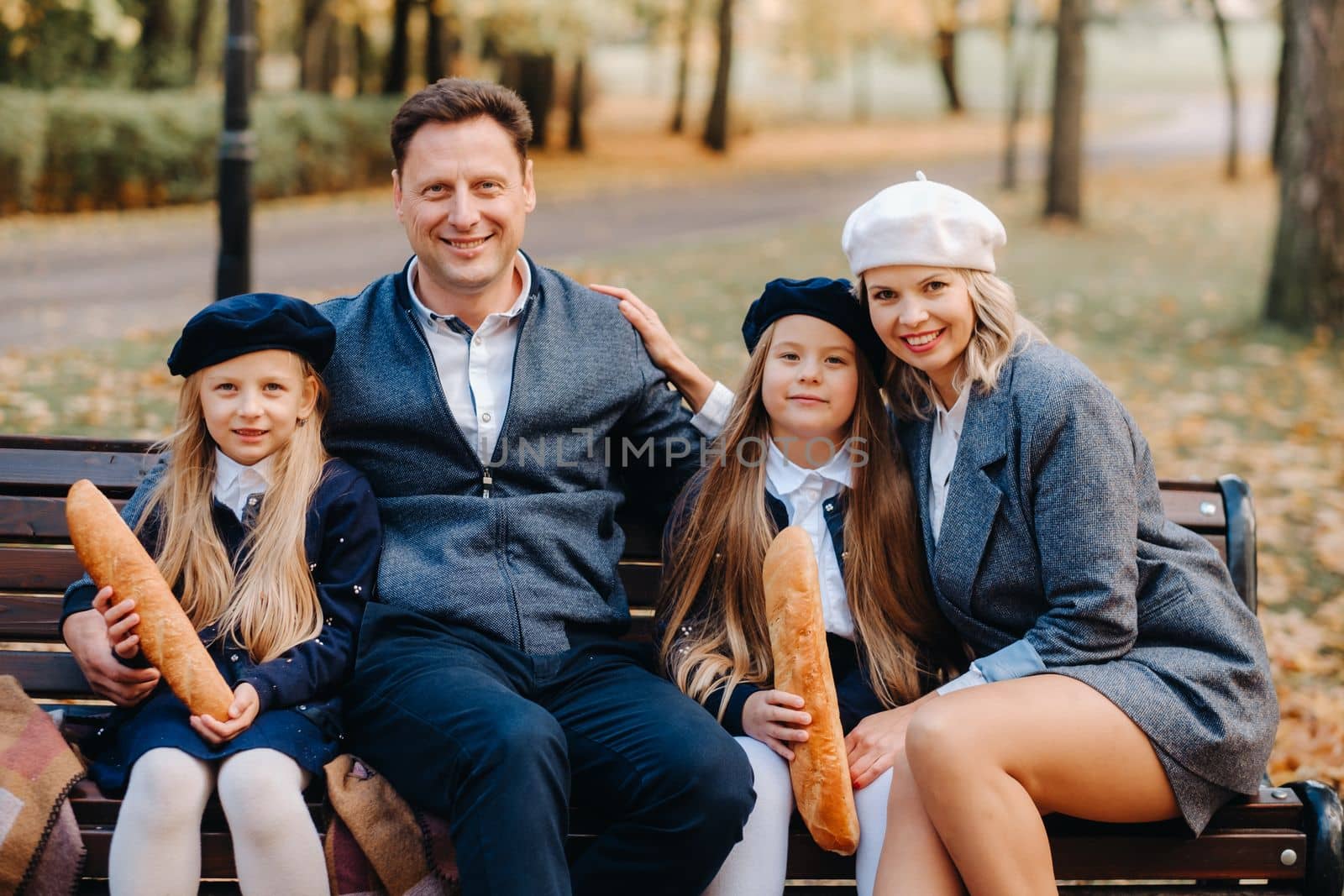 A large family is sitting on a bench in an autumn park. Happy people in the autumn park.