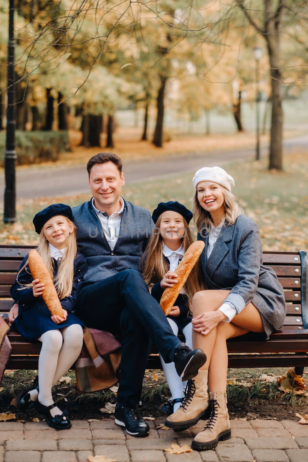 A large family is sitting on a bench in an autumn park. Happy people in the autumn park by Lobachad