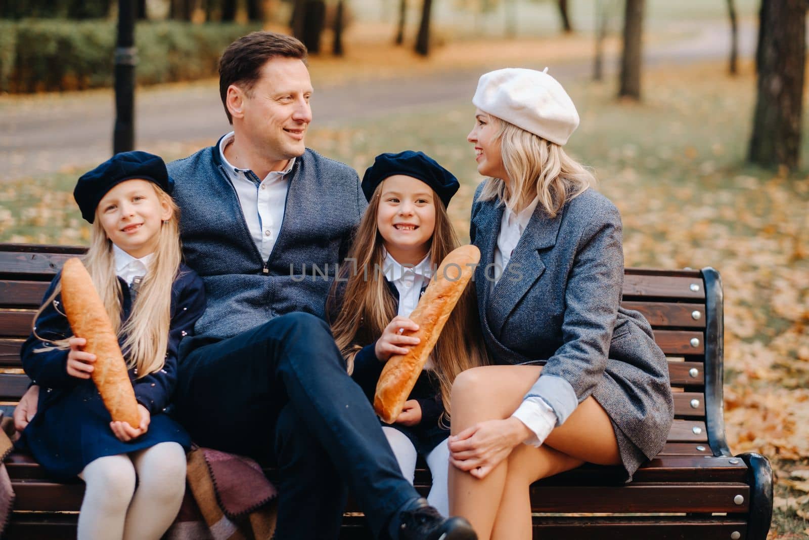 A large family is sitting on a bench in an autumn park. Happy people in the autumn park.