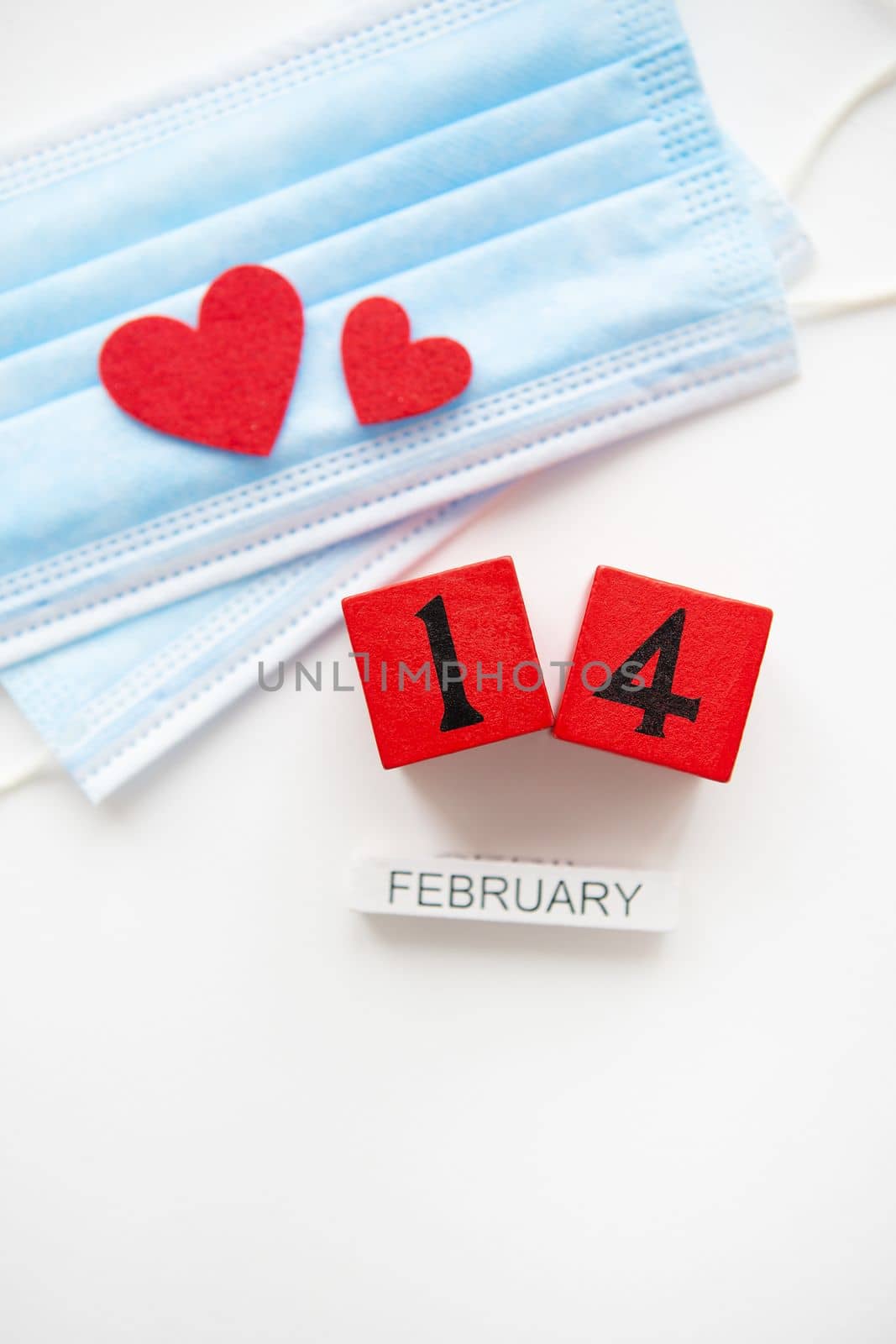 Valentine's Day celebration concept. Wooden cubes on February 14th. The heart lies on medical masks, the fight against coronavirus