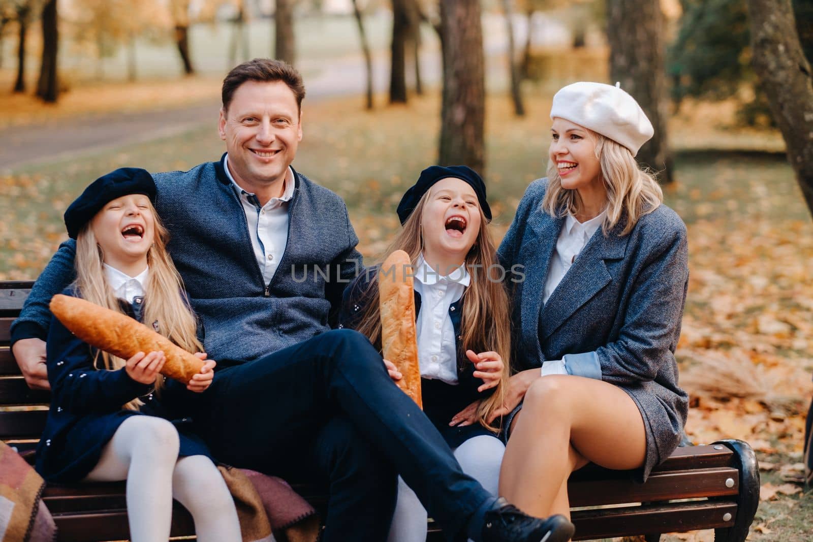 A large family is sitting on a bench in an autumn park. Happy people in the autumn park.