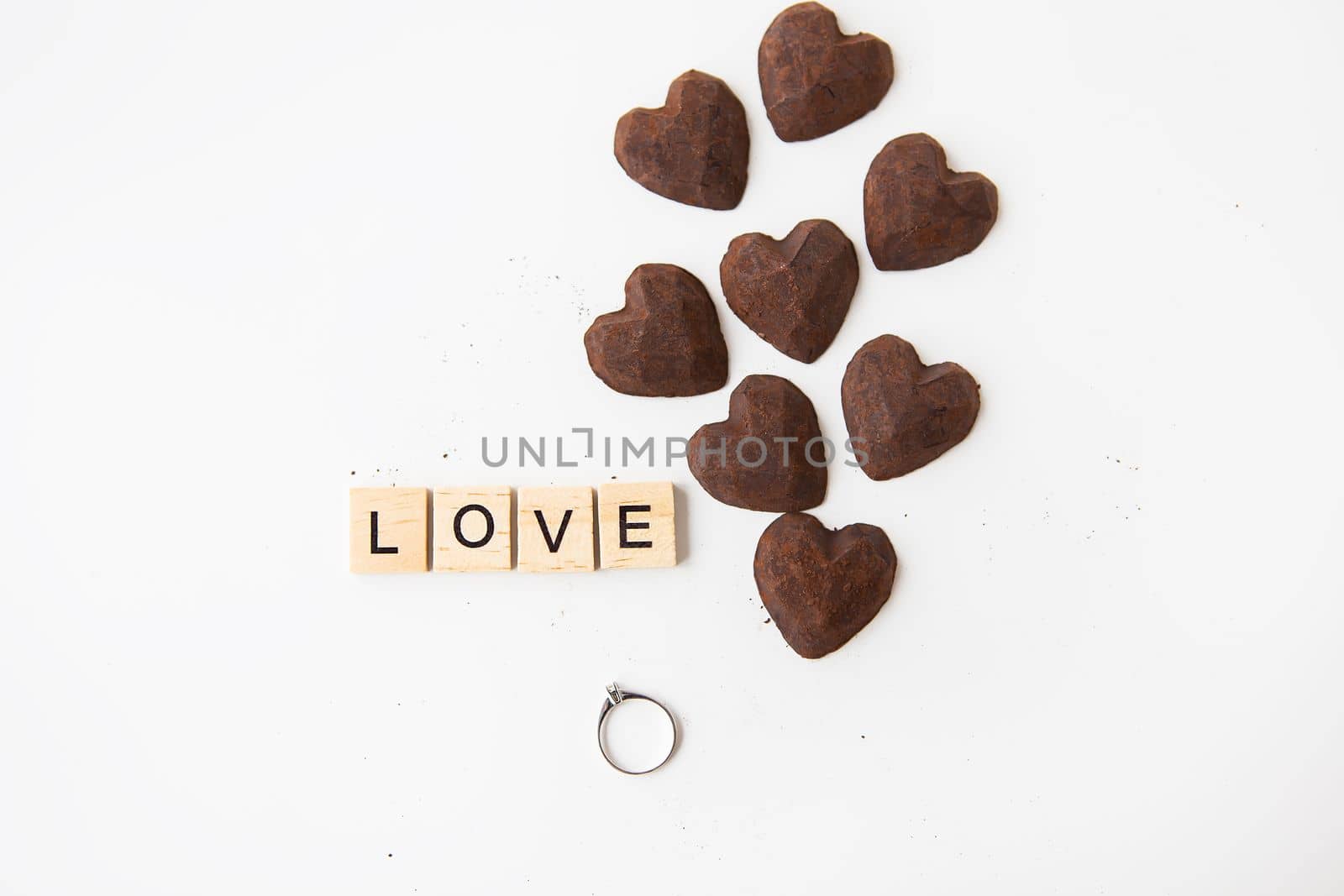 The inscription in wooden letters love, small truffle candies in the form of a heart. Ring with a diamond - a proposal of a hand and a heart