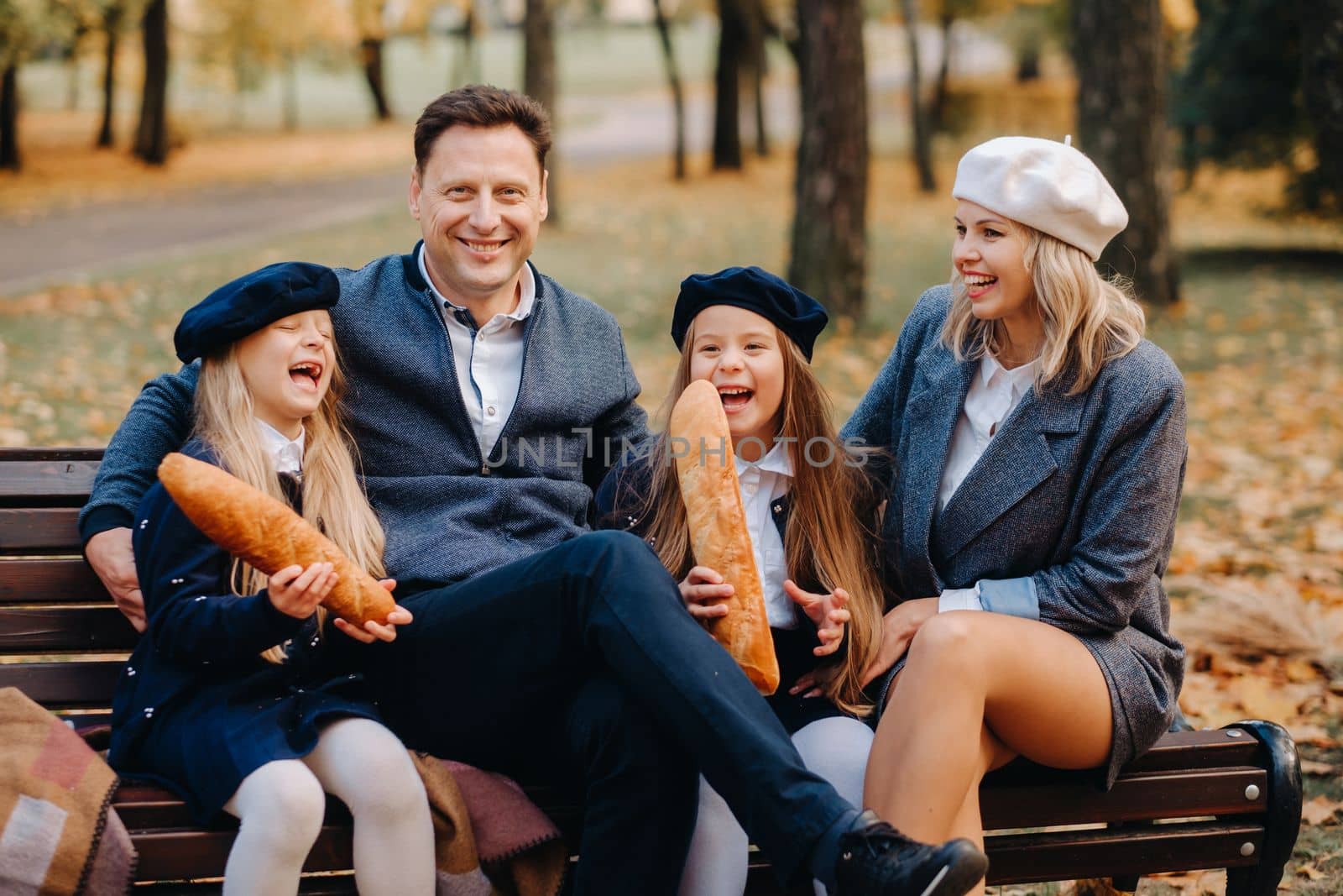 A large family is sitting on a bench in an autumn park. Happy people in the autumn park.