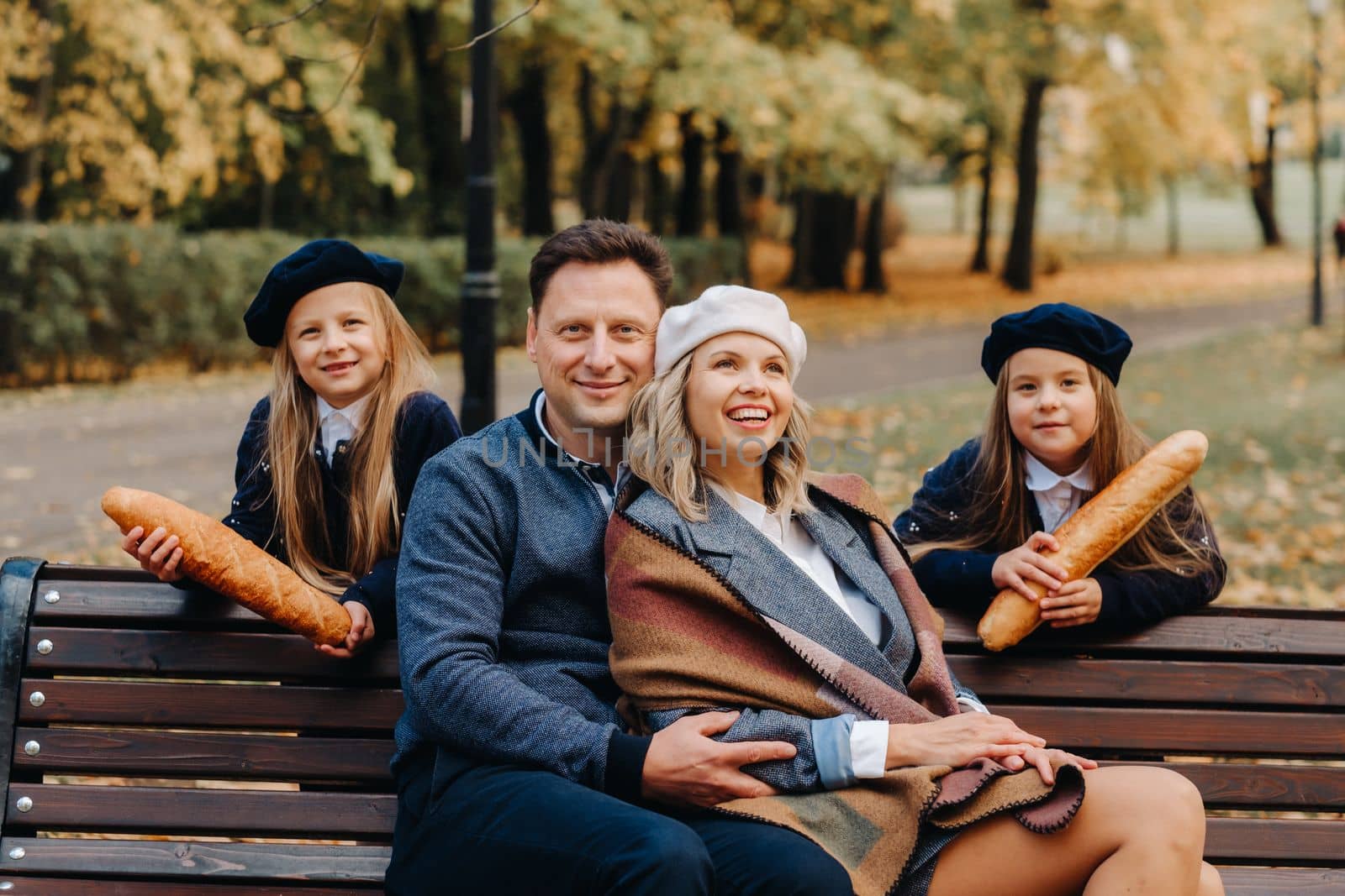 A large family is sitting on a bench in an autumn park. Happy people in the autumn park.