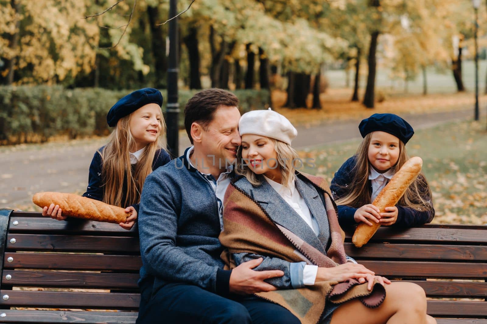 A large family is sitting on a bench in an autumn park. Happy people in the autumn park.