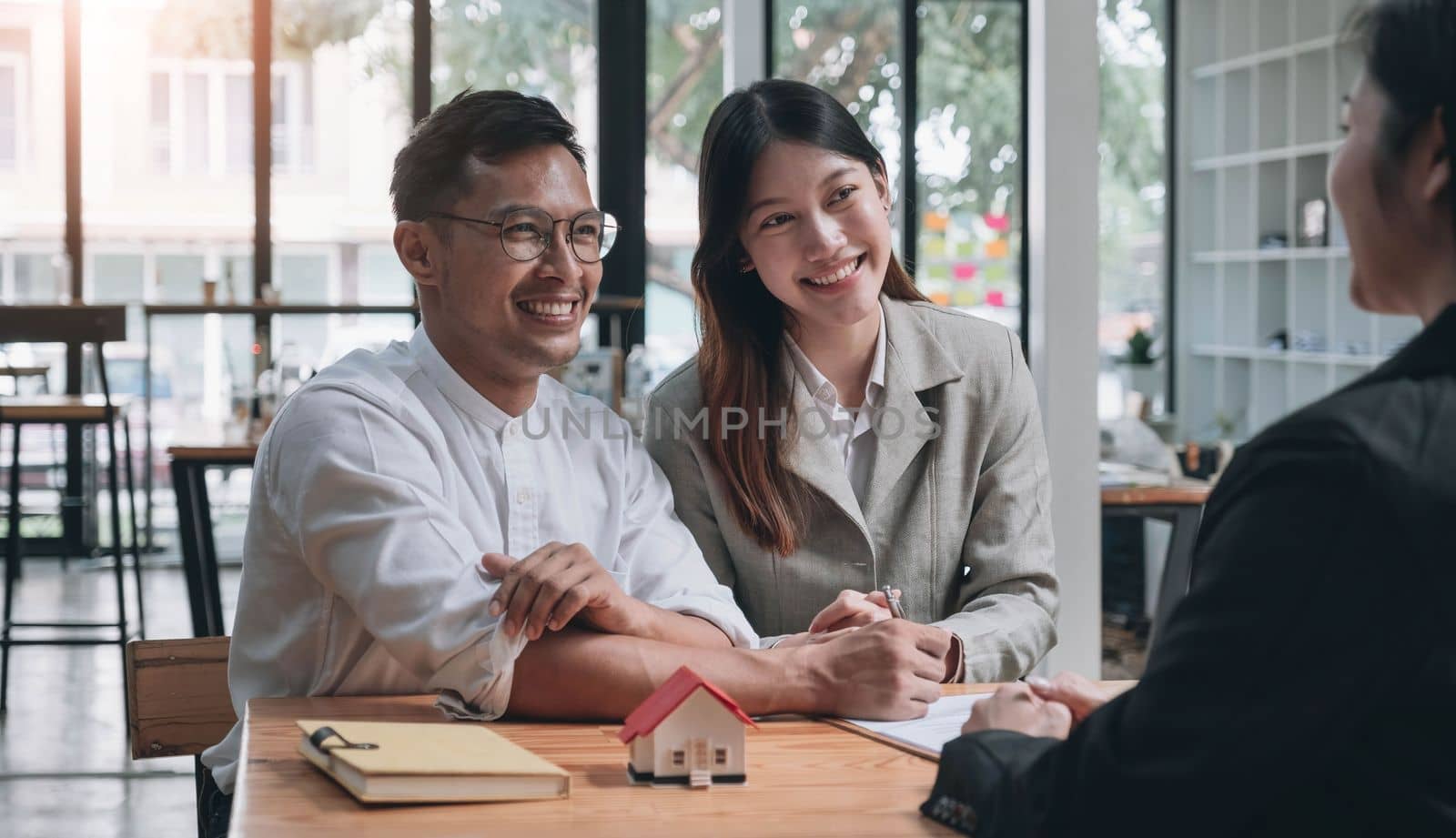 Horizontal view happy married couple wife asian ethnicity husband signing rental contract at meeting with realtor or landlord, first property purchase, mortgage and loan ownership concept.