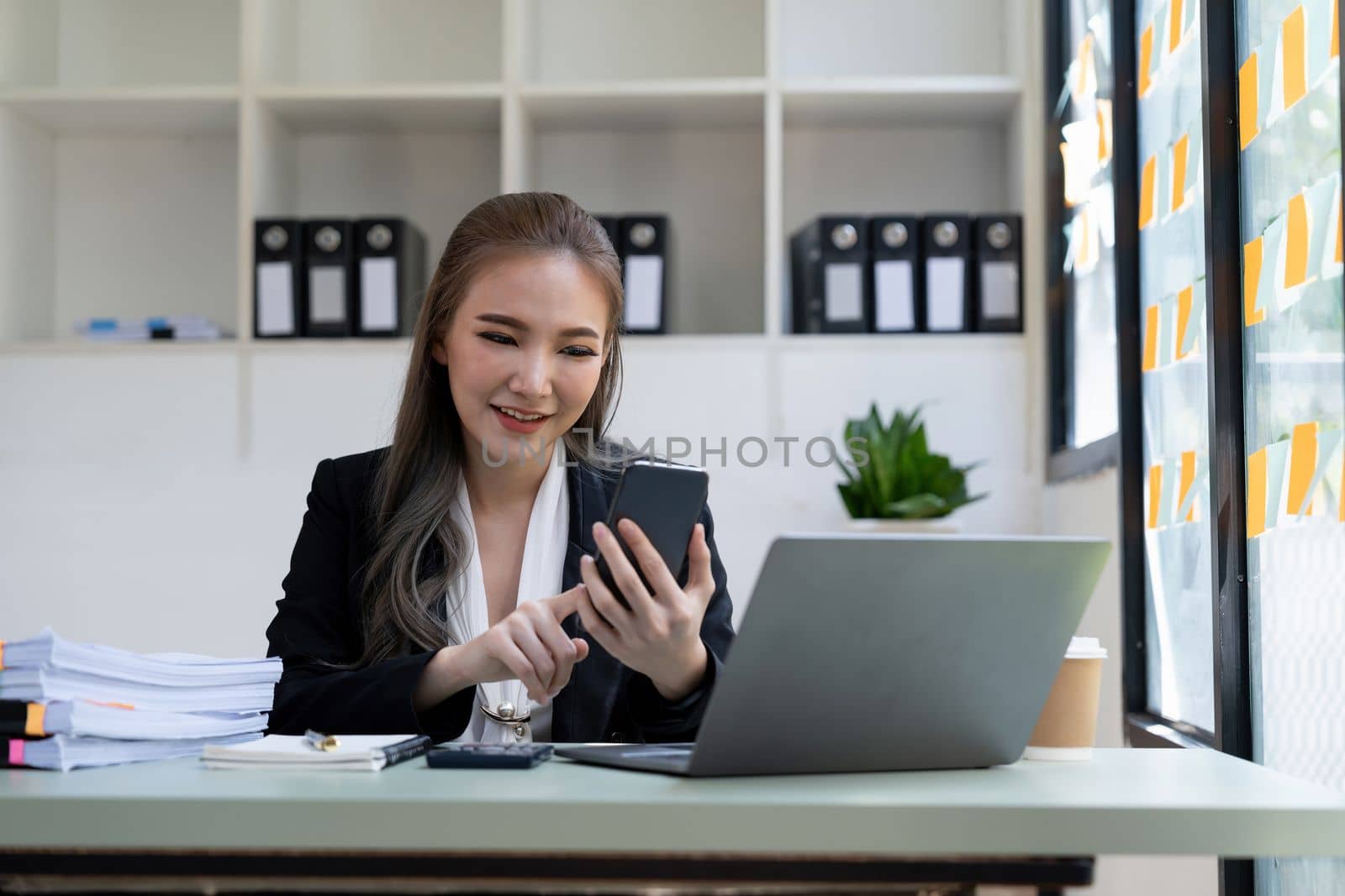 Beautiful young business woman using phone in office.