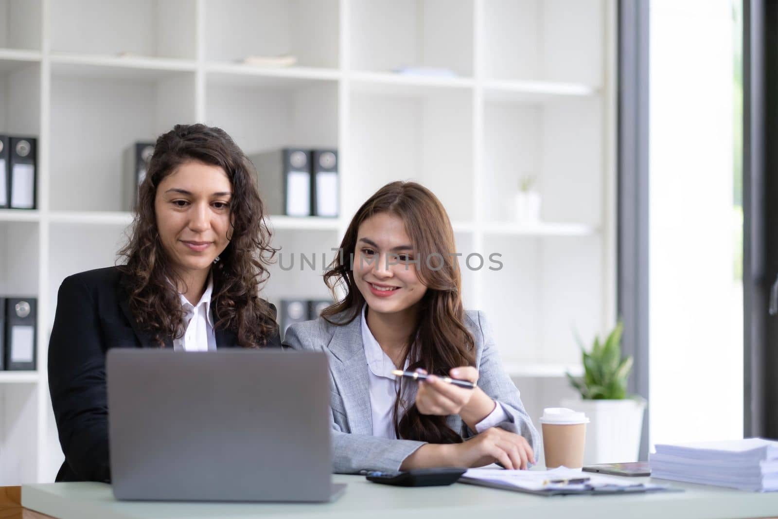 Two young Asian business woman talk, consult, discuss working with new startup project idea presentation analyze plan marketing and investment in the office. by wichayada