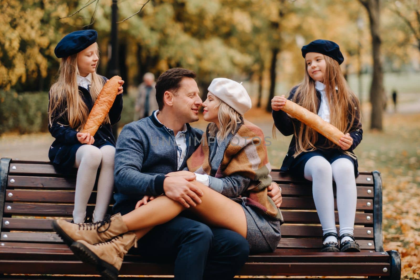 A large family is sitting on a bench in an autumn park. Happy people in the autumn park.