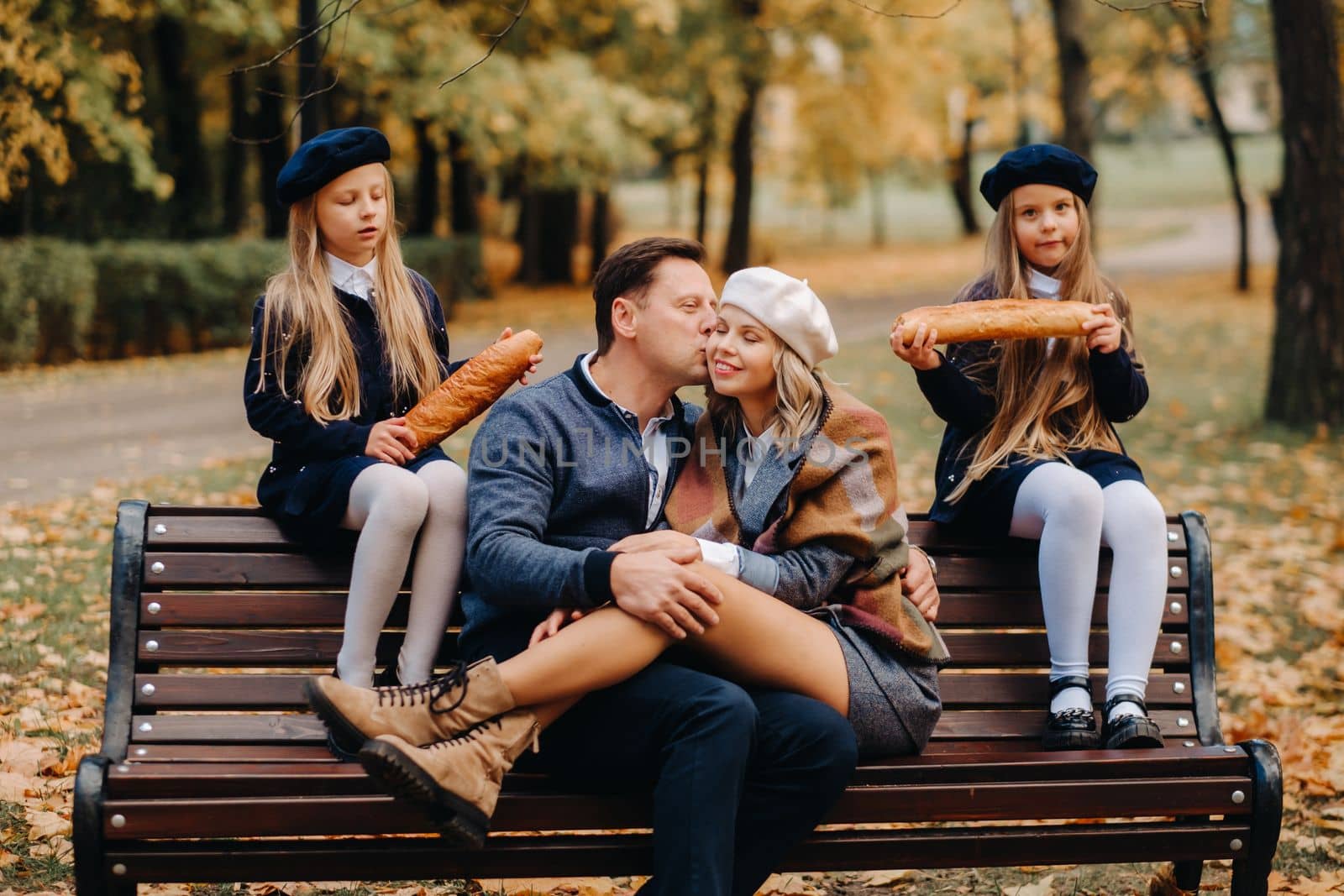 A large family is sitting on a bench in an autumn park. Happy people in the autumn park.