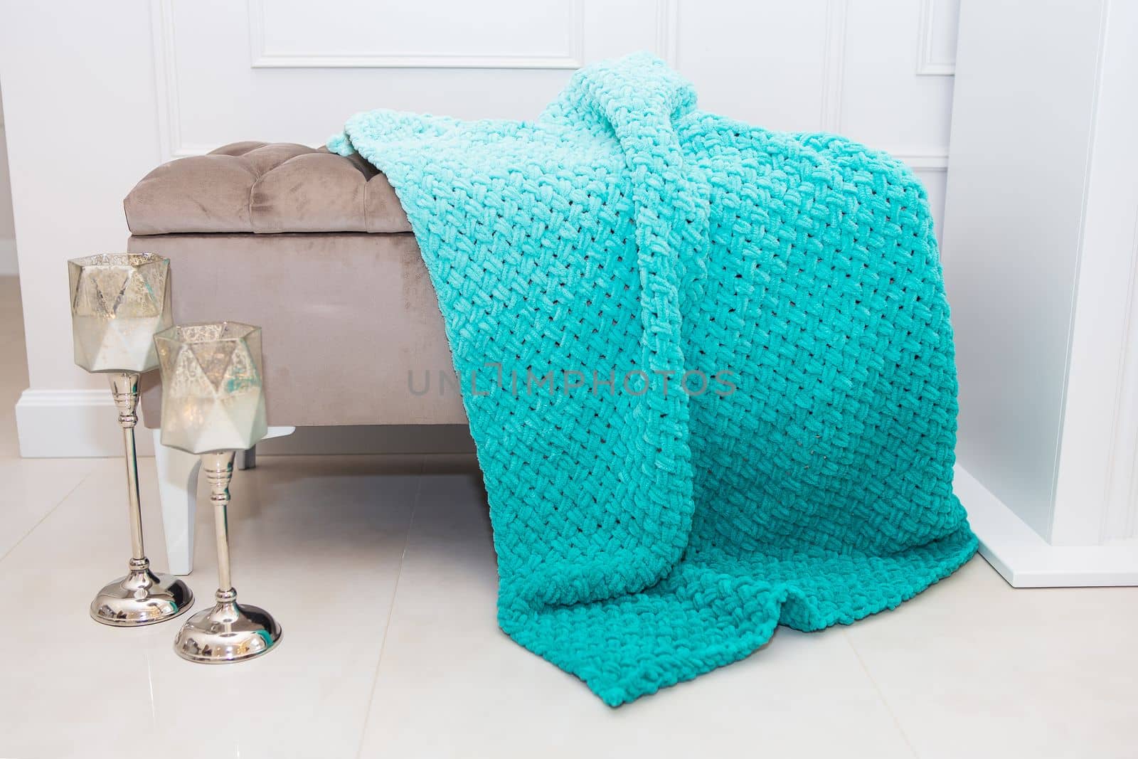 Background texture of plush fabric in aquamarine green color, background pattern of soft woolen material that lies on a small sofa along with candlesticks, cozy concept