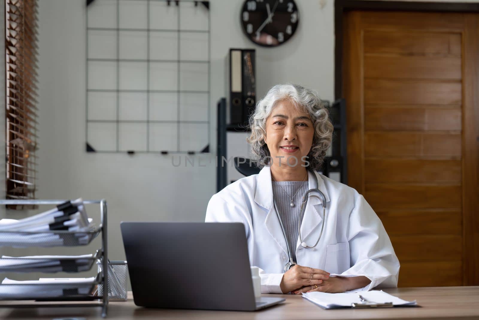 Portrait of Asian doctor working at her table in clinic.