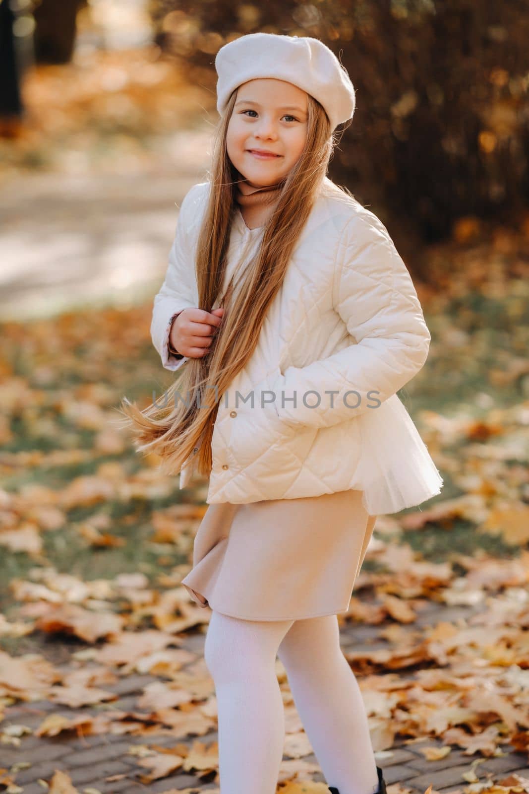 A happy girl in a cap walking in the autumn park.