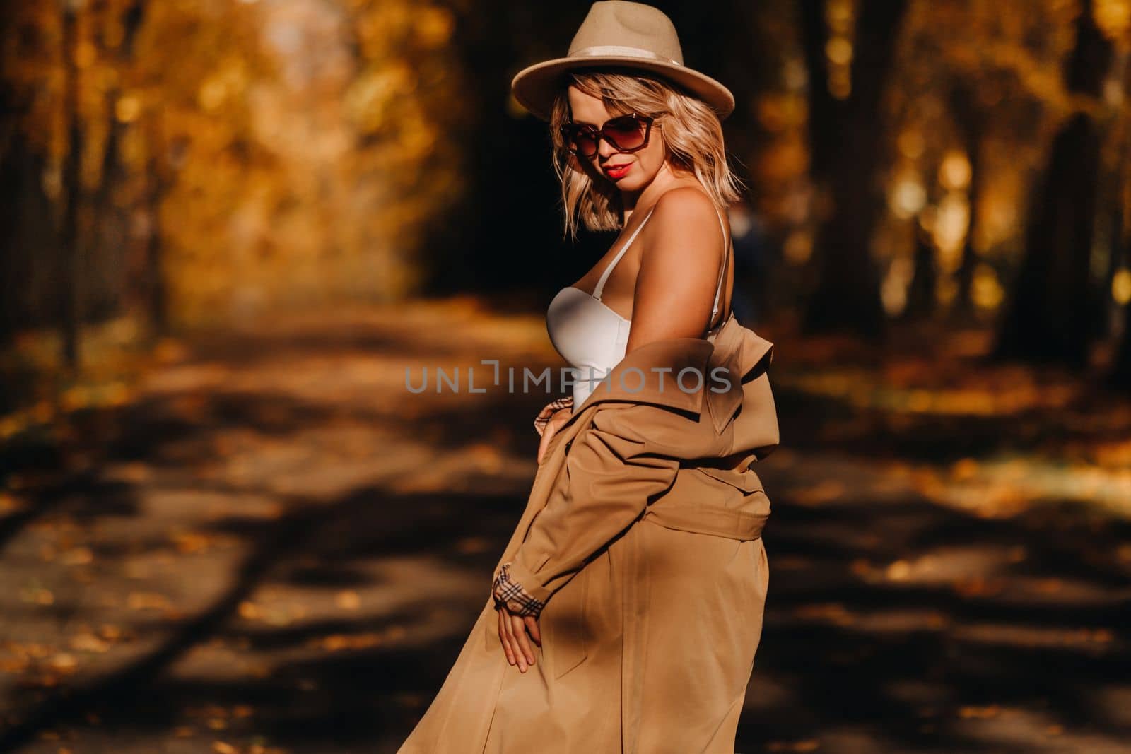 Sexy girl in a coat and hat in an autumn sunny park.