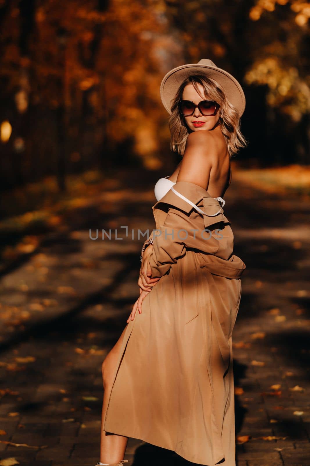 Sexy girl in a coat and hat in an autumn sunny park.