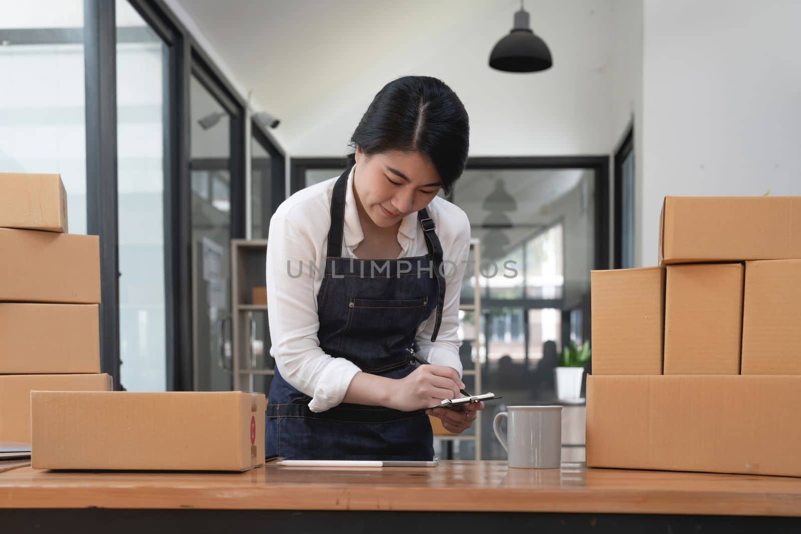 Happy young asian woman startup small business freelance with parcel box and computer laptop at home. Online marketing packing box delivery concept.