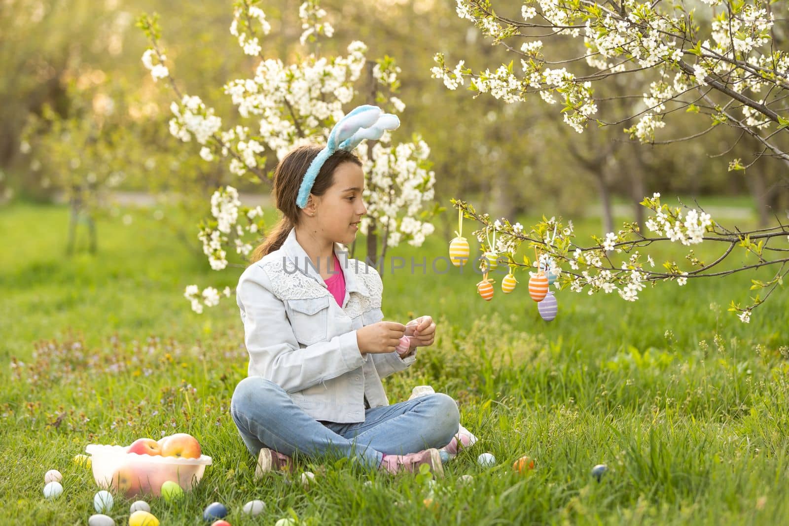 Adorable little girl on Easter holiday sitting on the grass