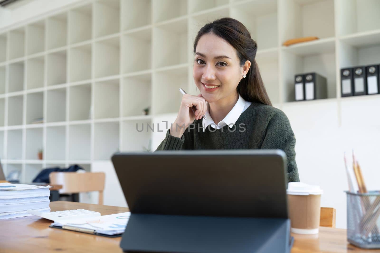 Portrait of smiling asian woman using laptop computer for financial paperwork analysis