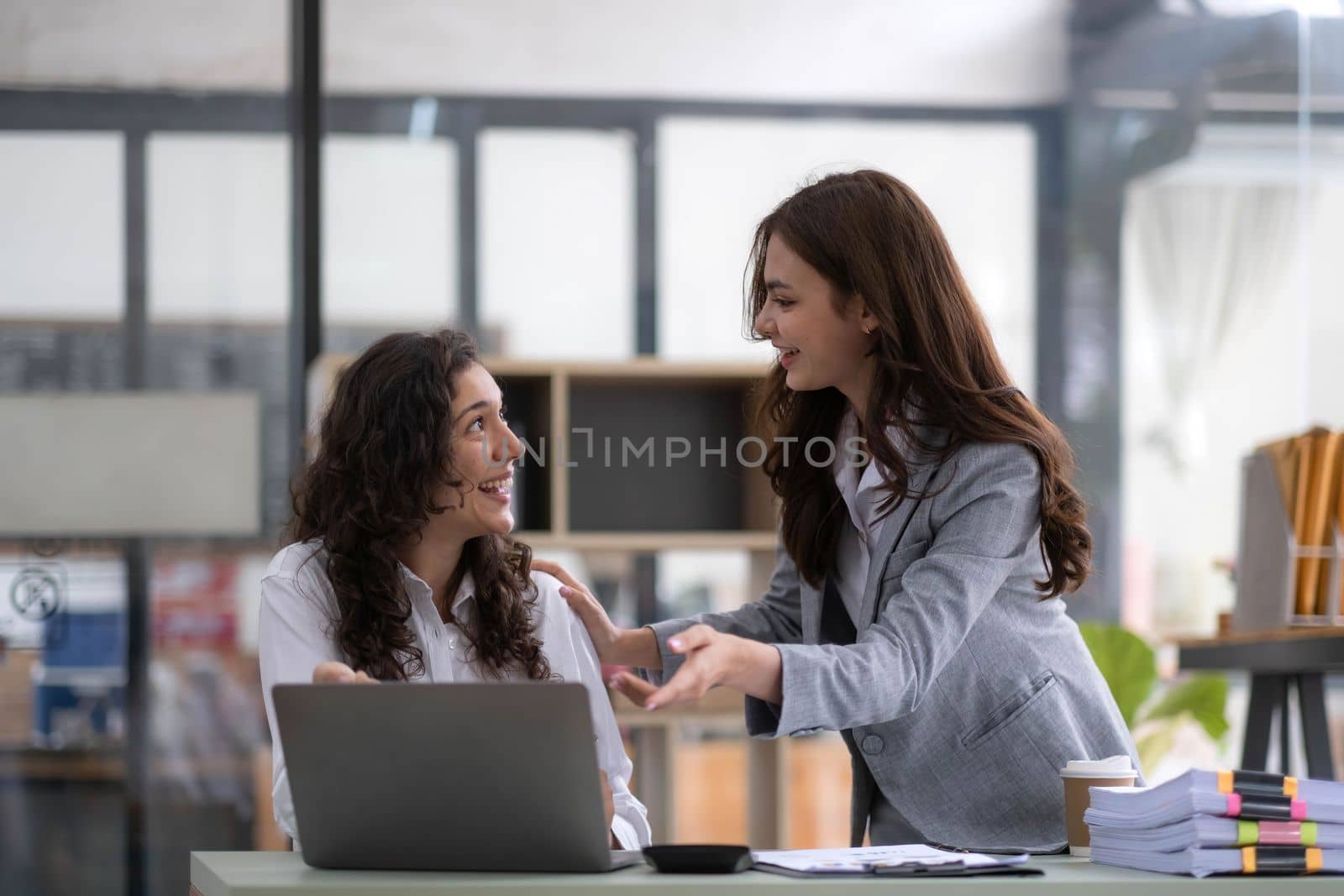 Two young Asian business woman talk, consult, discuss working with new startup project idea presentation analyze plan marketing and investment in the office. by wichayada