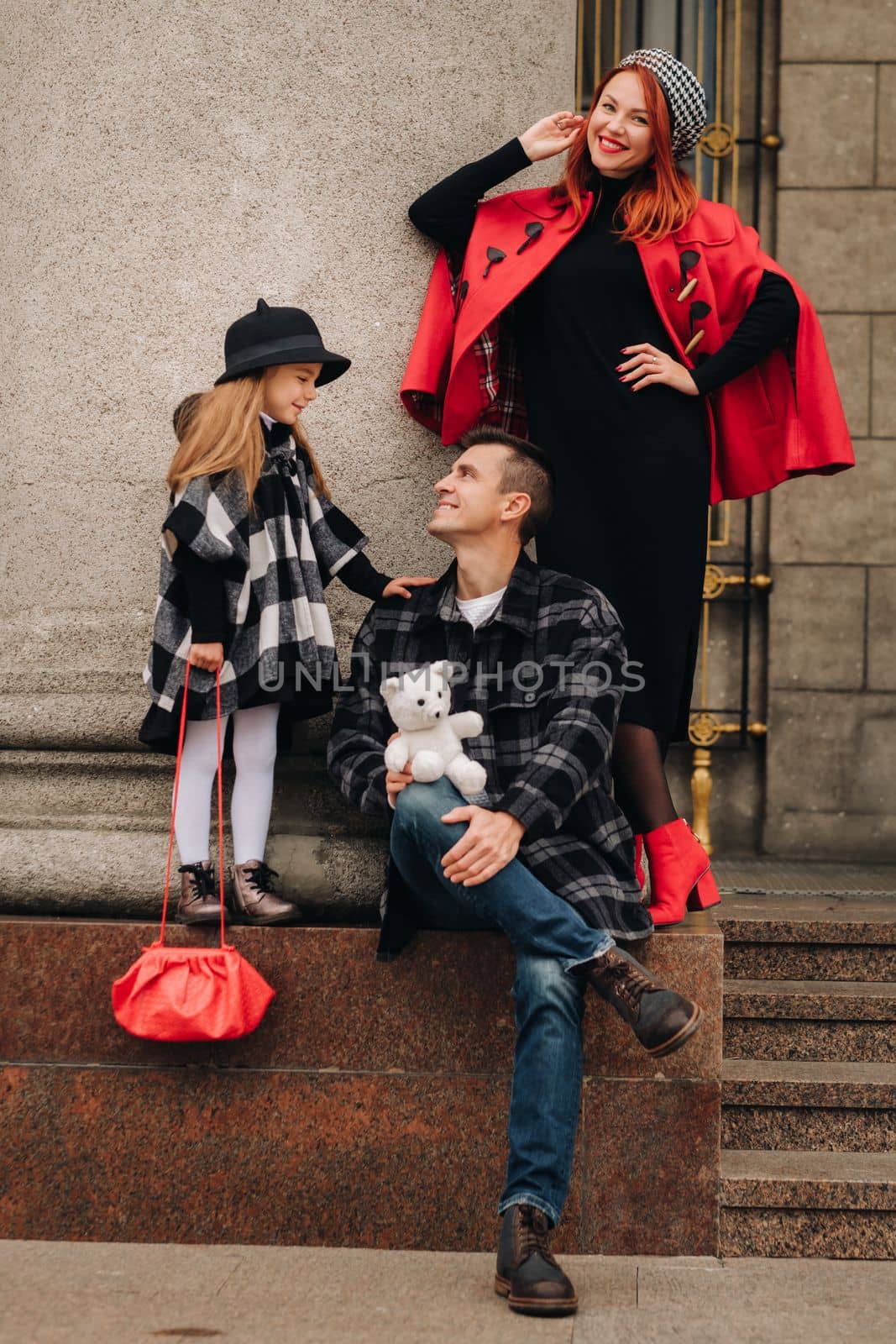 A stylish family of three strolls through the autumn city posing for a photographer . Dad, mom and daughter in the autumn city by Lobachad
