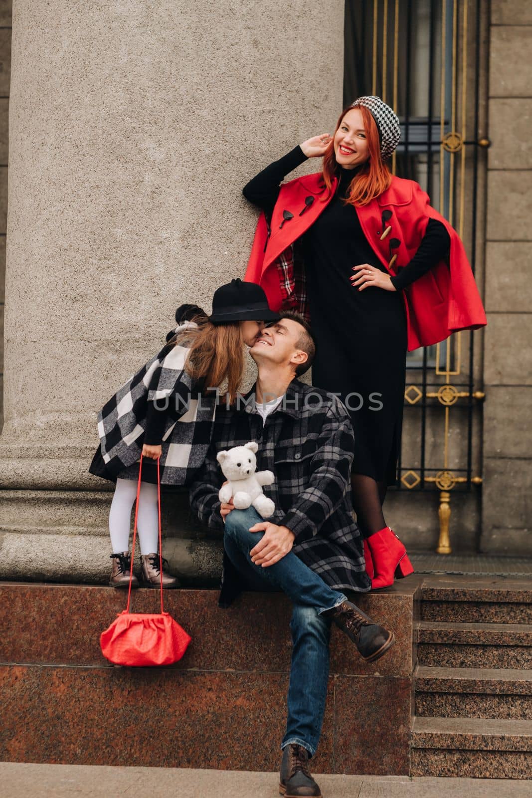 A stylish family of three strolls through the autumn city posing for a photographer . Dad, mom and daughter in the autumn city.