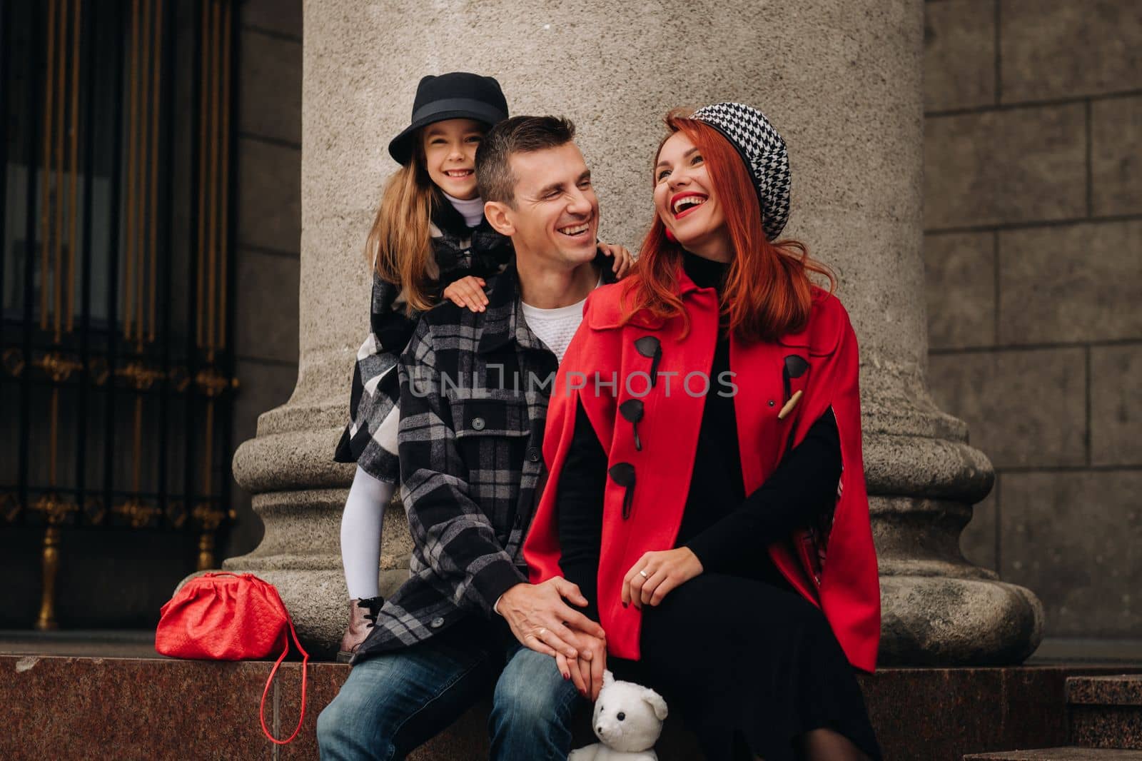 A stylish family of three strolls through the autumn city posing for a photographer . Dad, mom and daughter in the autumn city by Lobachad