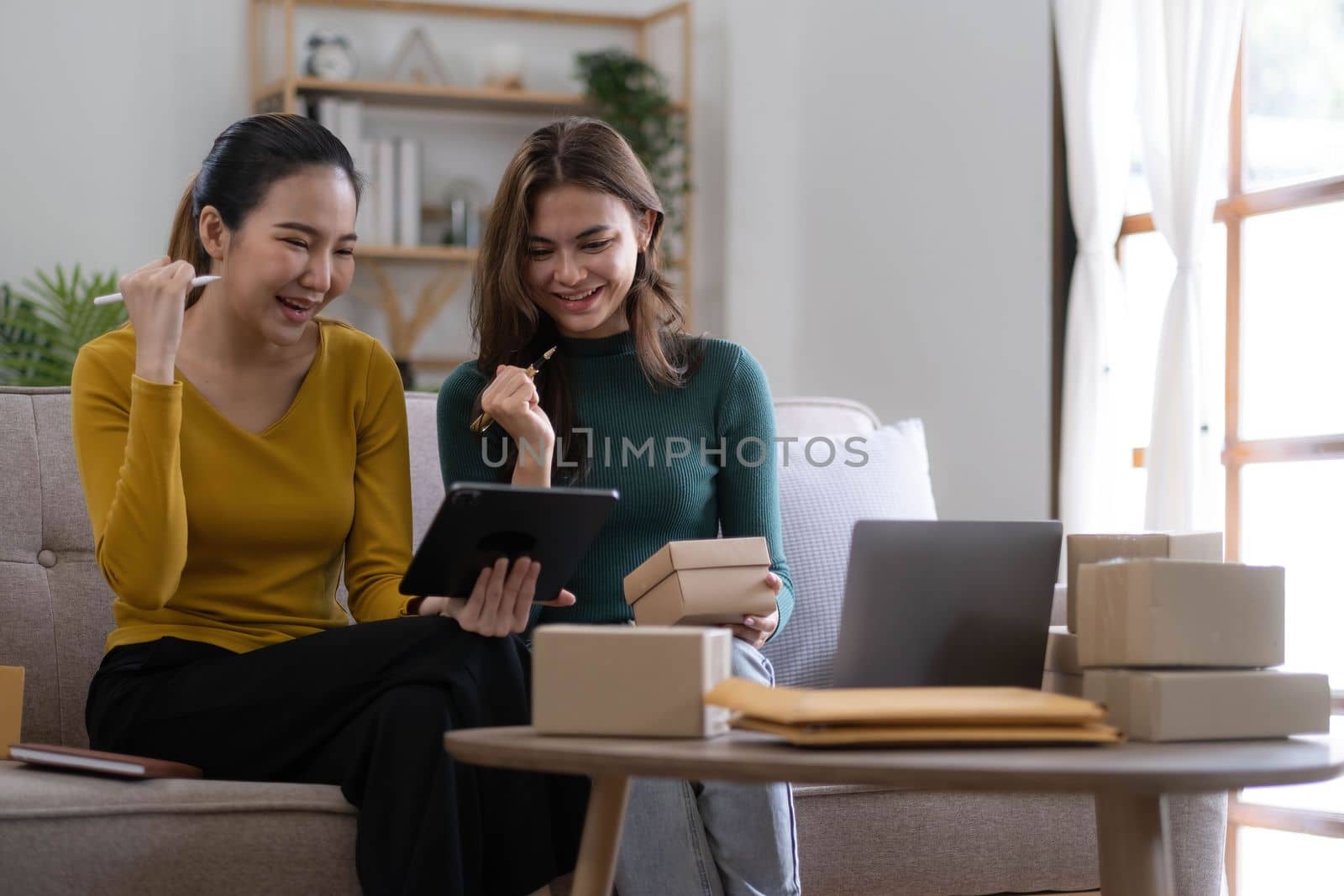 Portrait of Starting small businesses SME owners, two Asian woman check online orders Selling products working with boxs freelance work at home office, sme business online small medium enterprise by wichayada