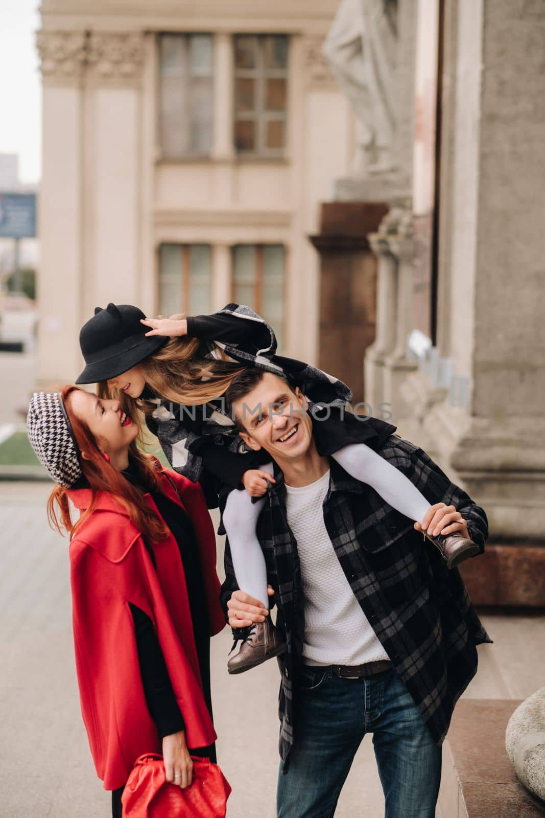 A stylish family of three strolls through the autumn city posing for a photographer . Dad, mom and daughter in the autumn city by Lobachad