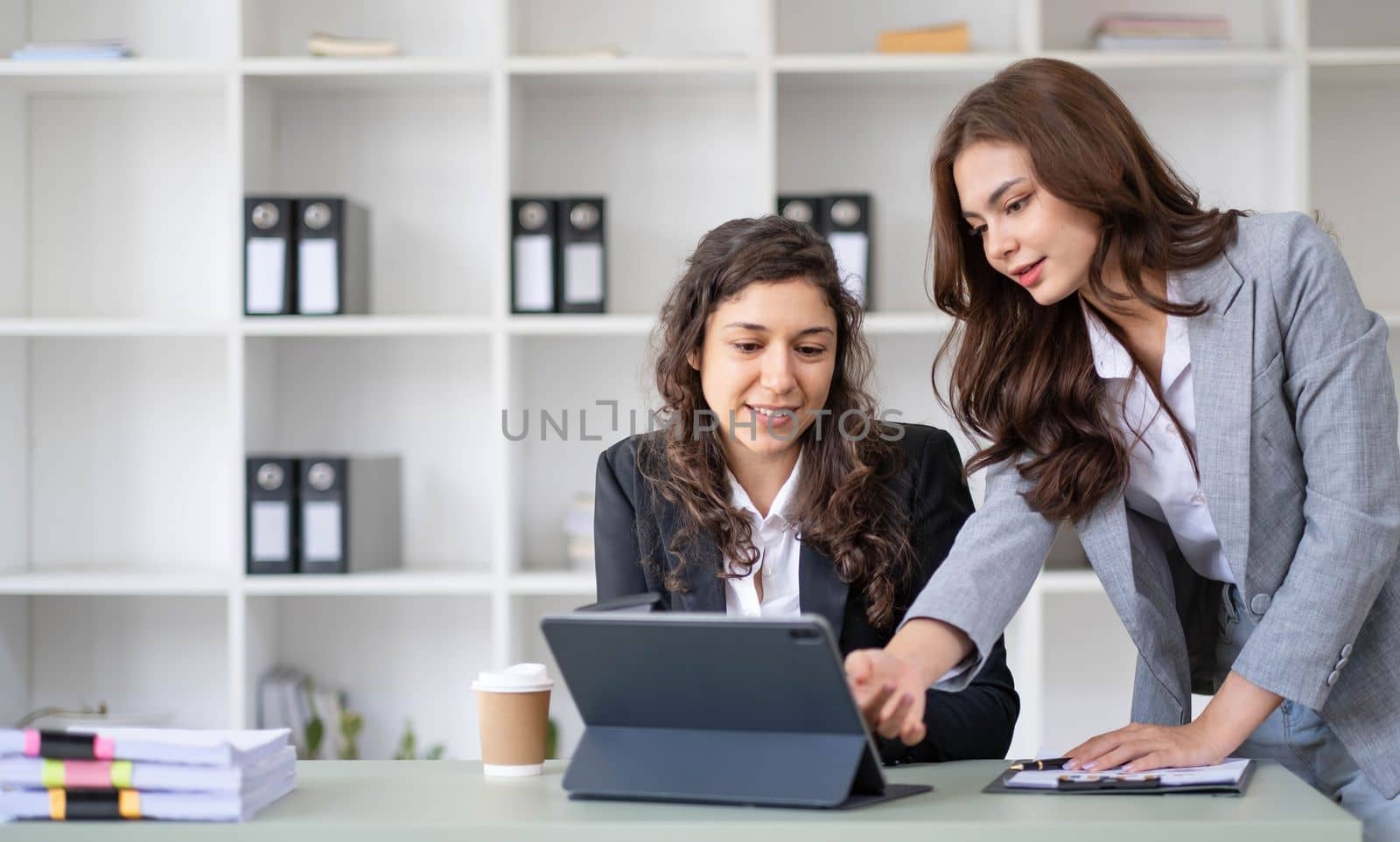 Two young Asian business woman talk, consult, discuss working with new startup project idea presentation analyze plan marketing and investment in the office. by wichayada