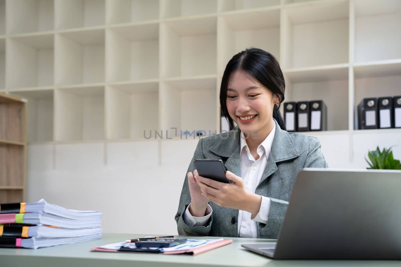 Beautiful young business woman using phone in office.