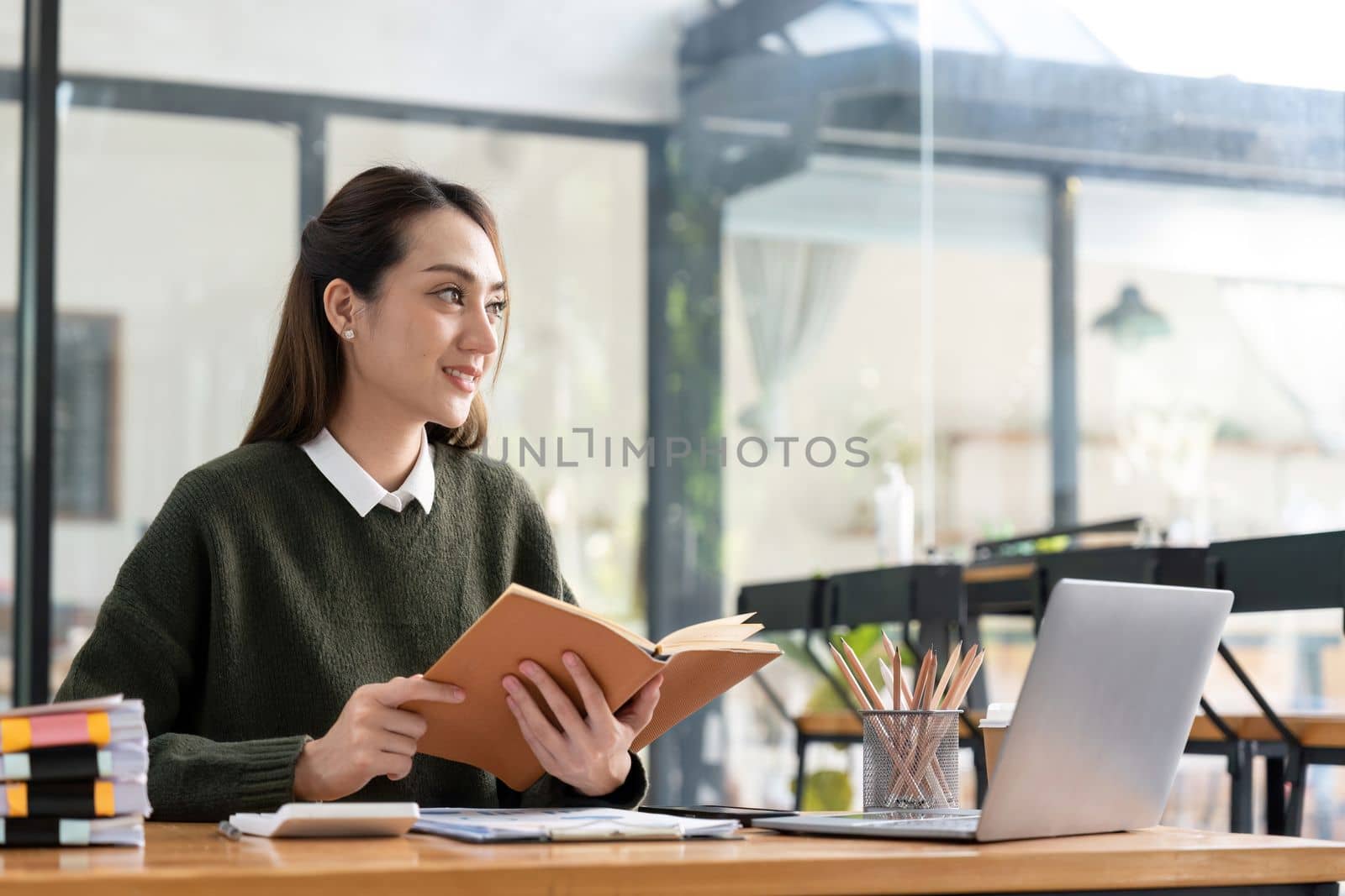 studying remotely from home, using a laptop, taking notes on notepad during online lesson, e-learning concept, smiling.