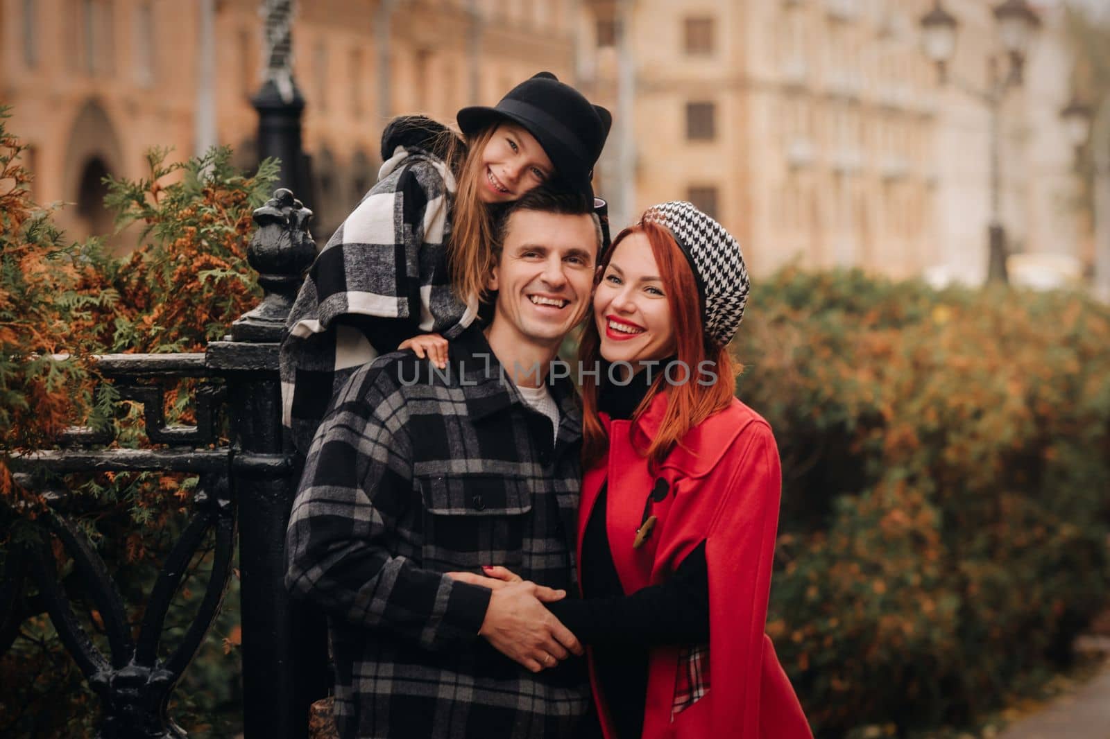 A stylish family of three strolls through the autumn city posing for a photographer . Dad, mom and daughter in the autumn city.