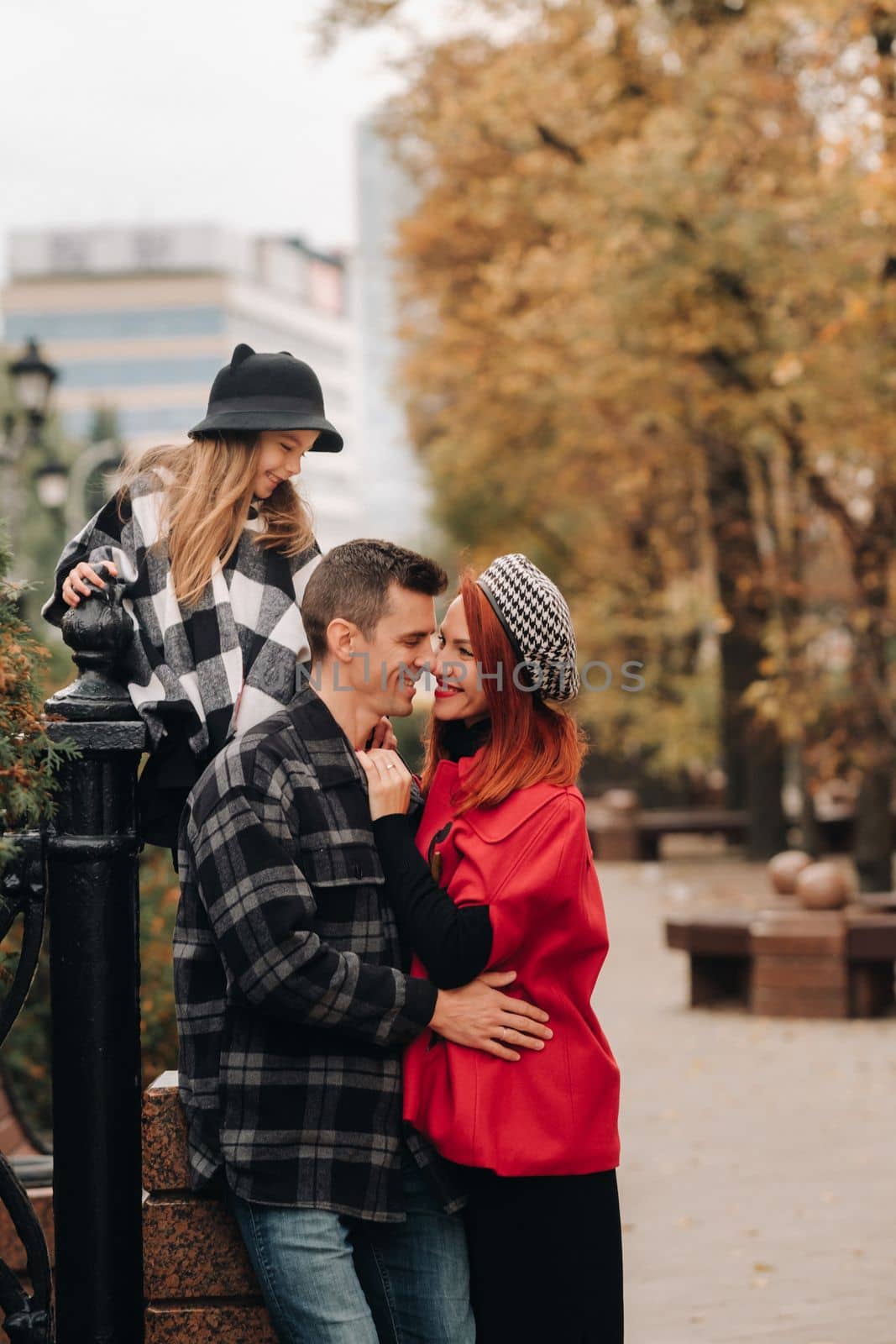 A stylish family of three strolls through the autumn city posing for a photographer . Dad, mom and daughter in the autumn city by Lobachad