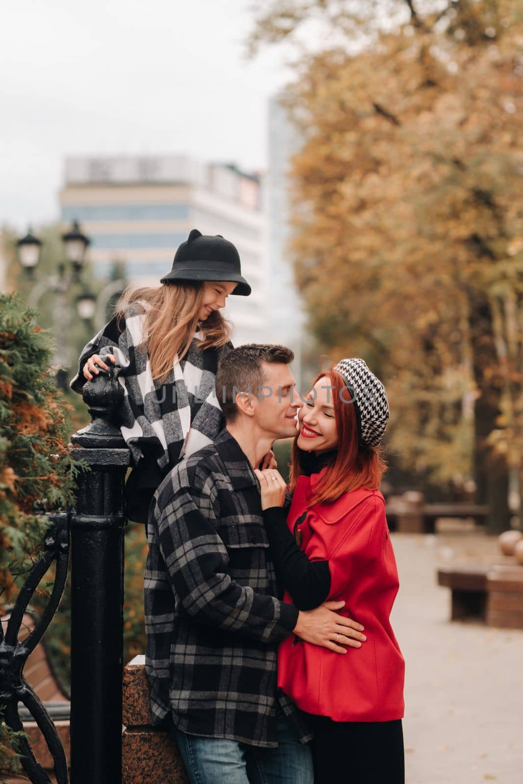 A stylish family of three strolls through the autumn city posing for a photographer . Dad, mom and daughter in the autumn city.