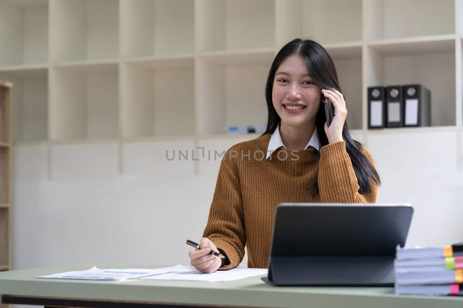 Portrait young asian businesswoman beautiful charming smiling and talking on the mobile phone in the office