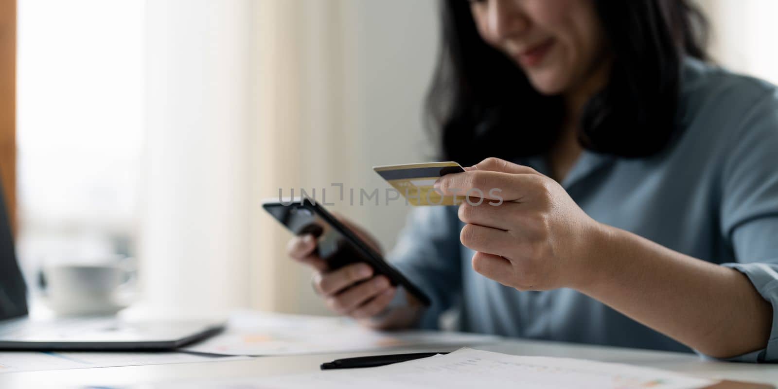 woman hand holding credit card with using smartphone for online shopping while making orders at home. business, lifestyle, technology, ecommerce, digital banking and online payment concept.