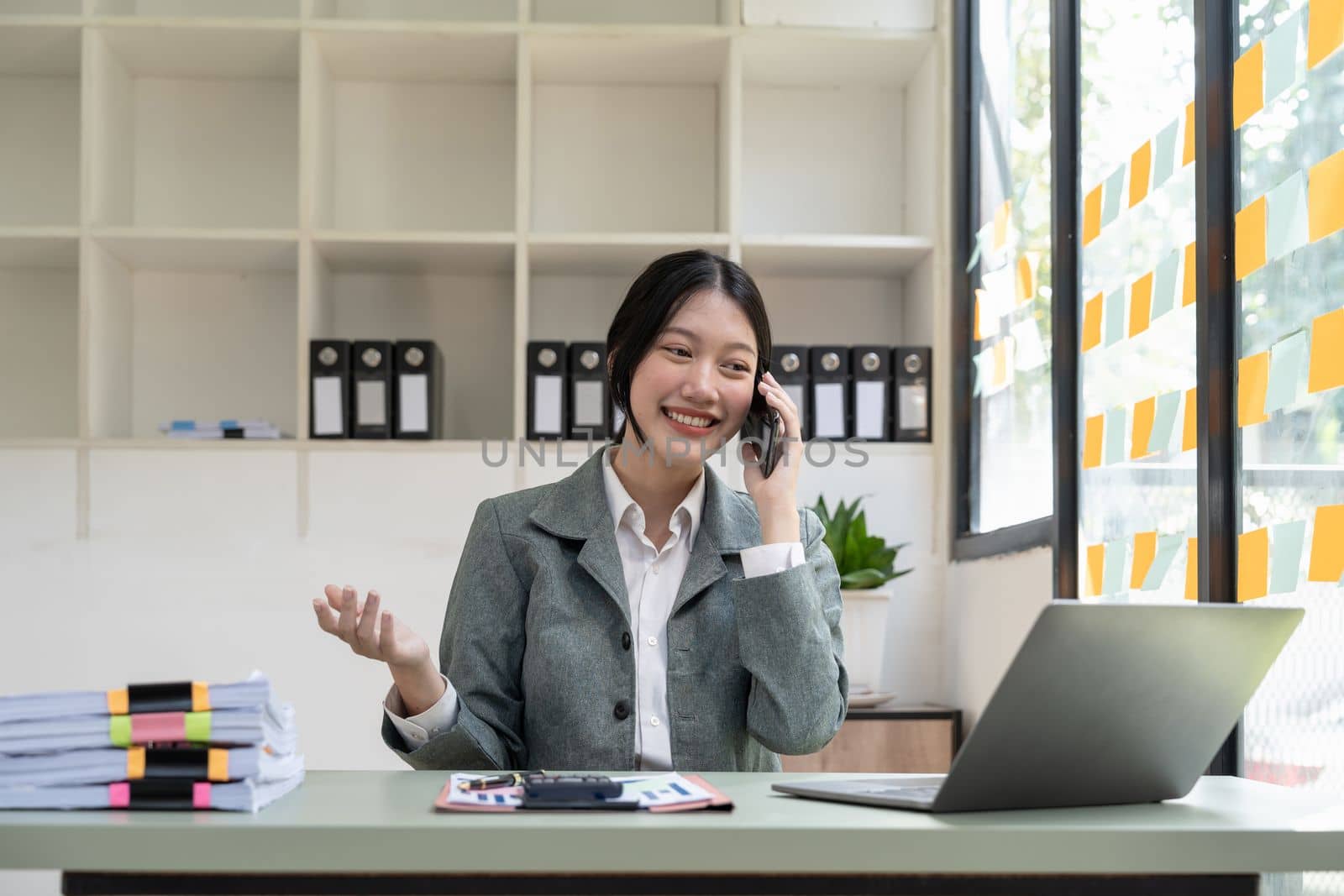 Young asian businesswoman beautiful charming smiling and talking on the mobile phone in the office