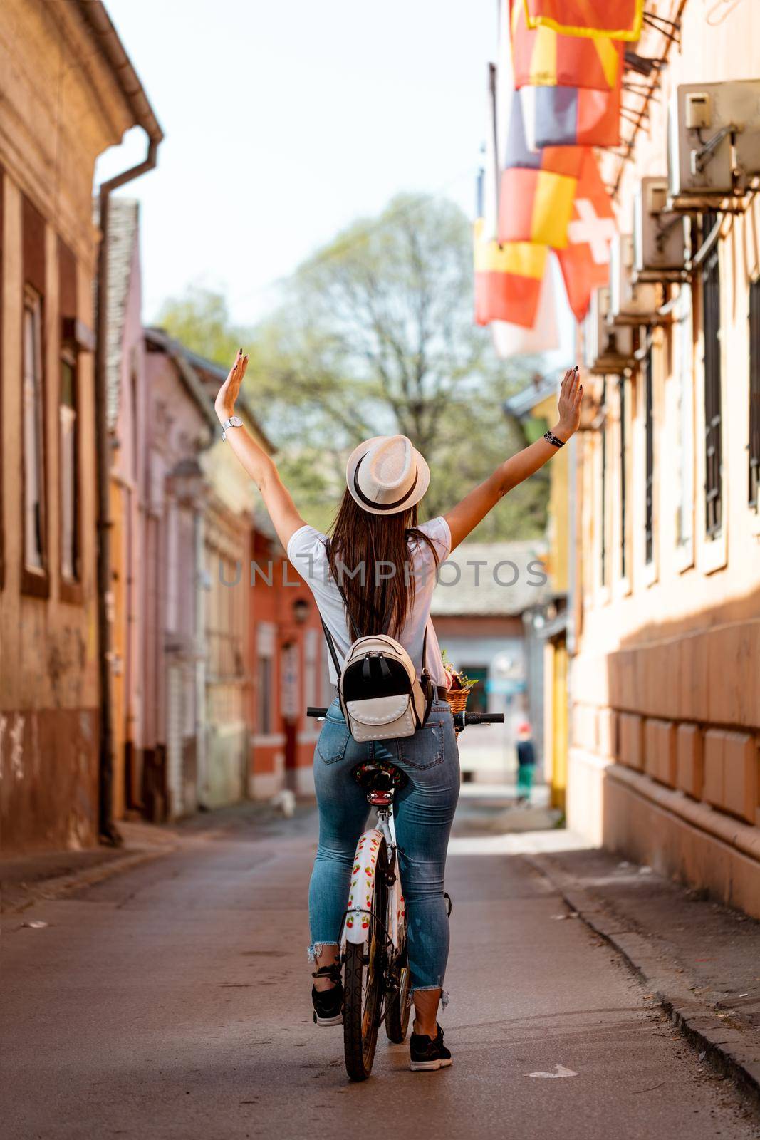 Rear view of a happy woman on bike cycling in summer sunny day, having fun of joy during outdoor activity. 