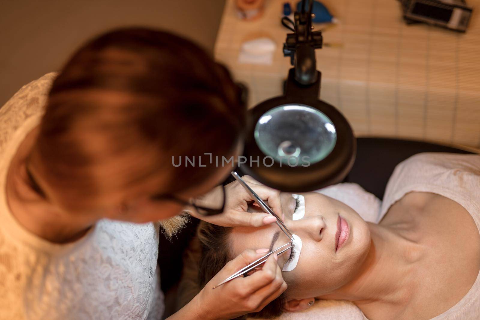 Beautician applying extended eyelashes to model at the beauty salon.