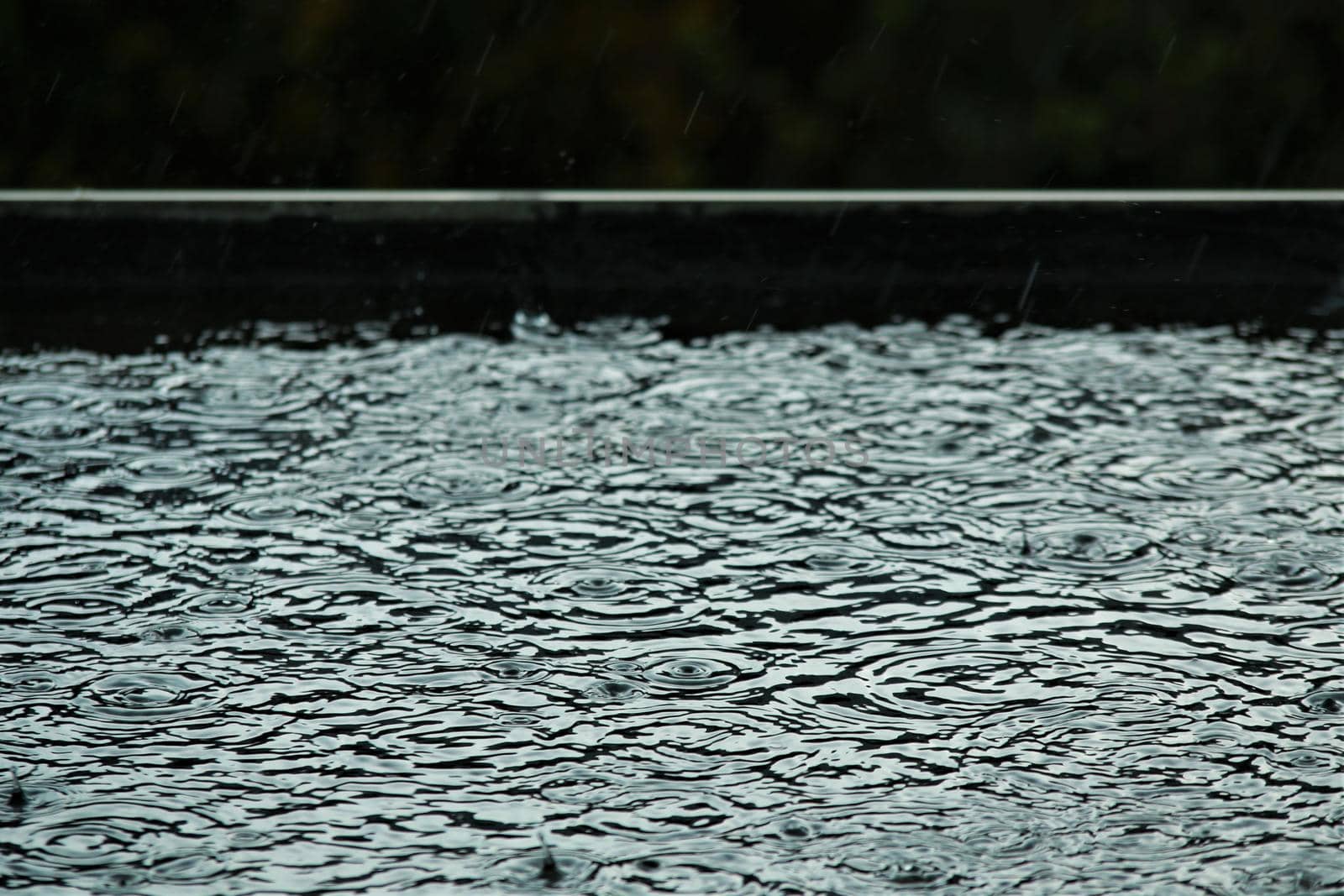 Rain makes circles on a black flat roof by Luise123
