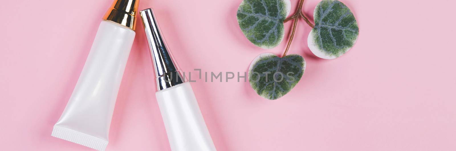 Mockup cosmetic tube with cream or lotion and leaf isolated on pink background, mock up package for advertising, skincare or cosmetology, top view, flat lay, skin care and treatment with product.