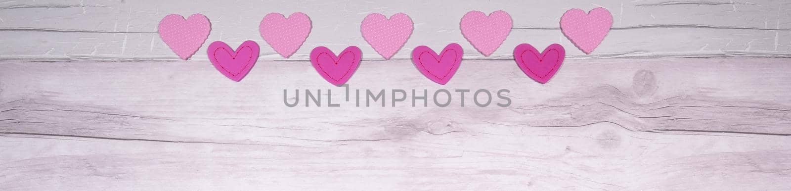 Pink felt hearts on a background of old wooden planks resembling an old parquet floor. Concept of valentines day and love in general by jp_chretien