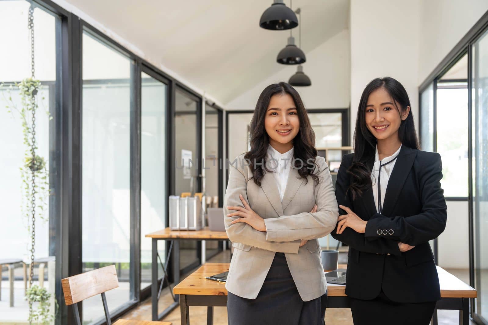 Happy two beautiful young Asian businesswoman standing discuss working together at office. by wichayada