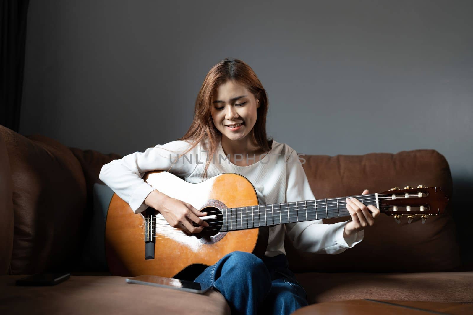 Image of happy beautiful woman playing guitar and composing song.