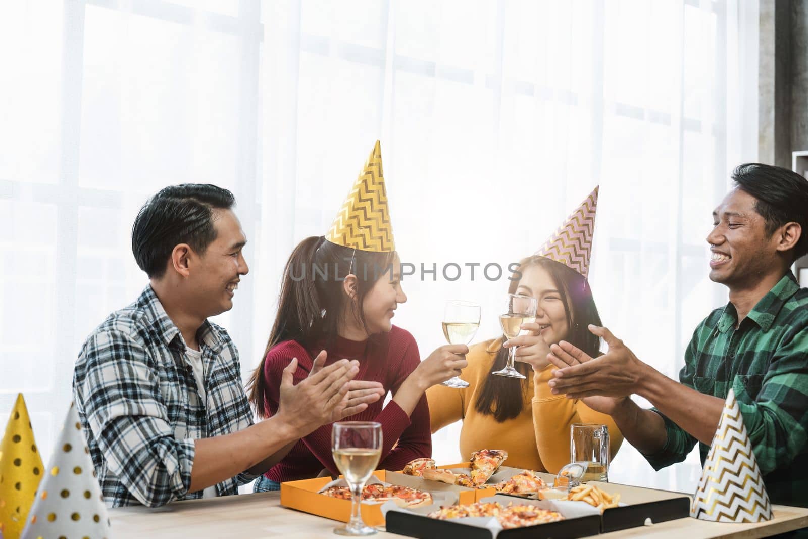 Group of happy colleagues having fun at a new year celebration ahead or business success. Coworkers with diverse ethnicities are toasting wine or champagne glasses at the office party.