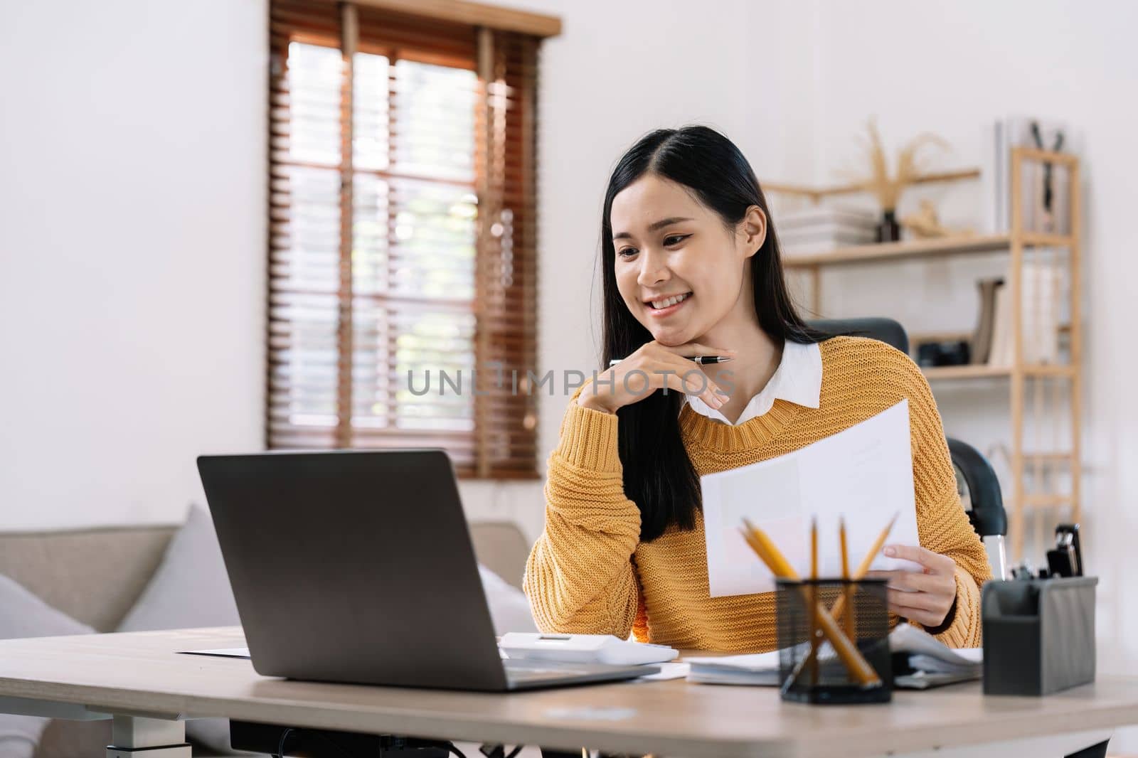 Beautiful young smiling asian businesswoman working on laptop and drinking coffee, Asia businesswoman working document finance and calculator in her office.