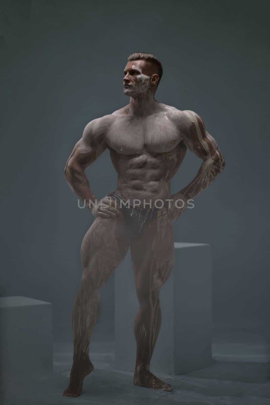 Studio shot of a muscular man. Young handsome athletic caucasian guy with beautiful naked torso looking away while posing shirtless isolated over grey background. Isolate.
