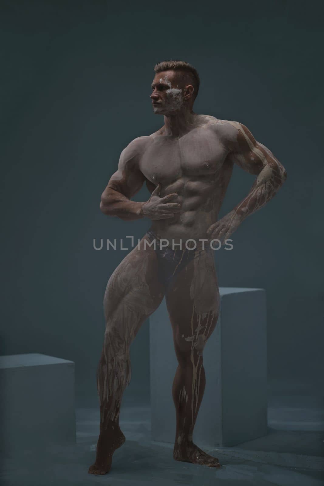 Studio shot of a muscular man. Young handsome athletic caucasian guy with beautiful naked torso looking away while posing shirtless isolated over grey background. Isolate.