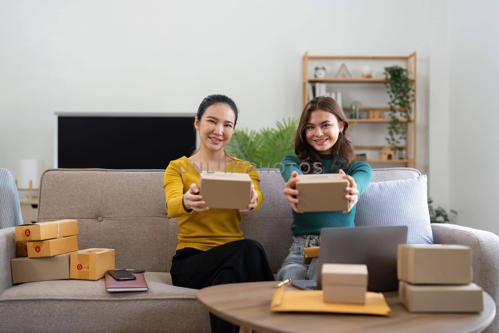 Young business woman working online e-commerce shopping at her shop. Young woman seller prepare parcel box of product for deliver to customer. Online selling, e-commerce