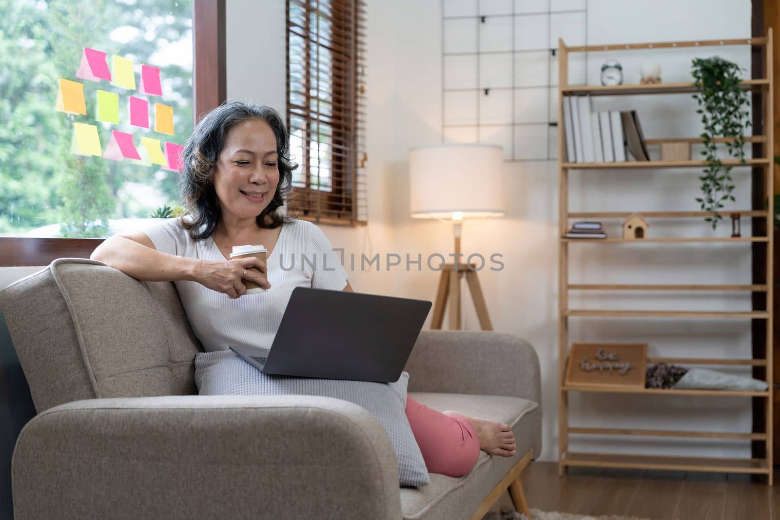 Happy senior asian woman working at home. Beautiful stylish elderly woman smiling and relaxing at home